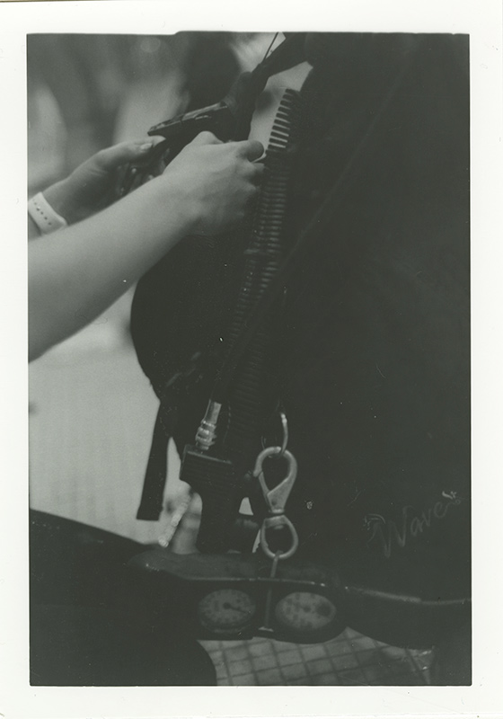 Close up film photograph of diver preparing their boyancy contorl device. Photo by Kirsten DeZeeuw